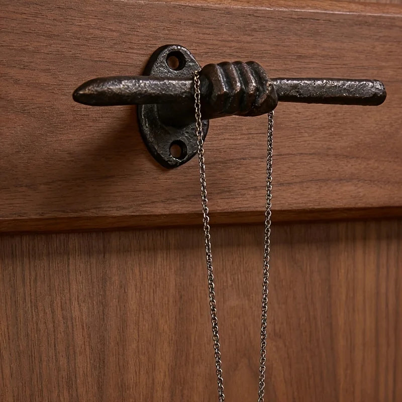 Rustic cast iron hand wall hook mounted on dark wood, holding a necklace