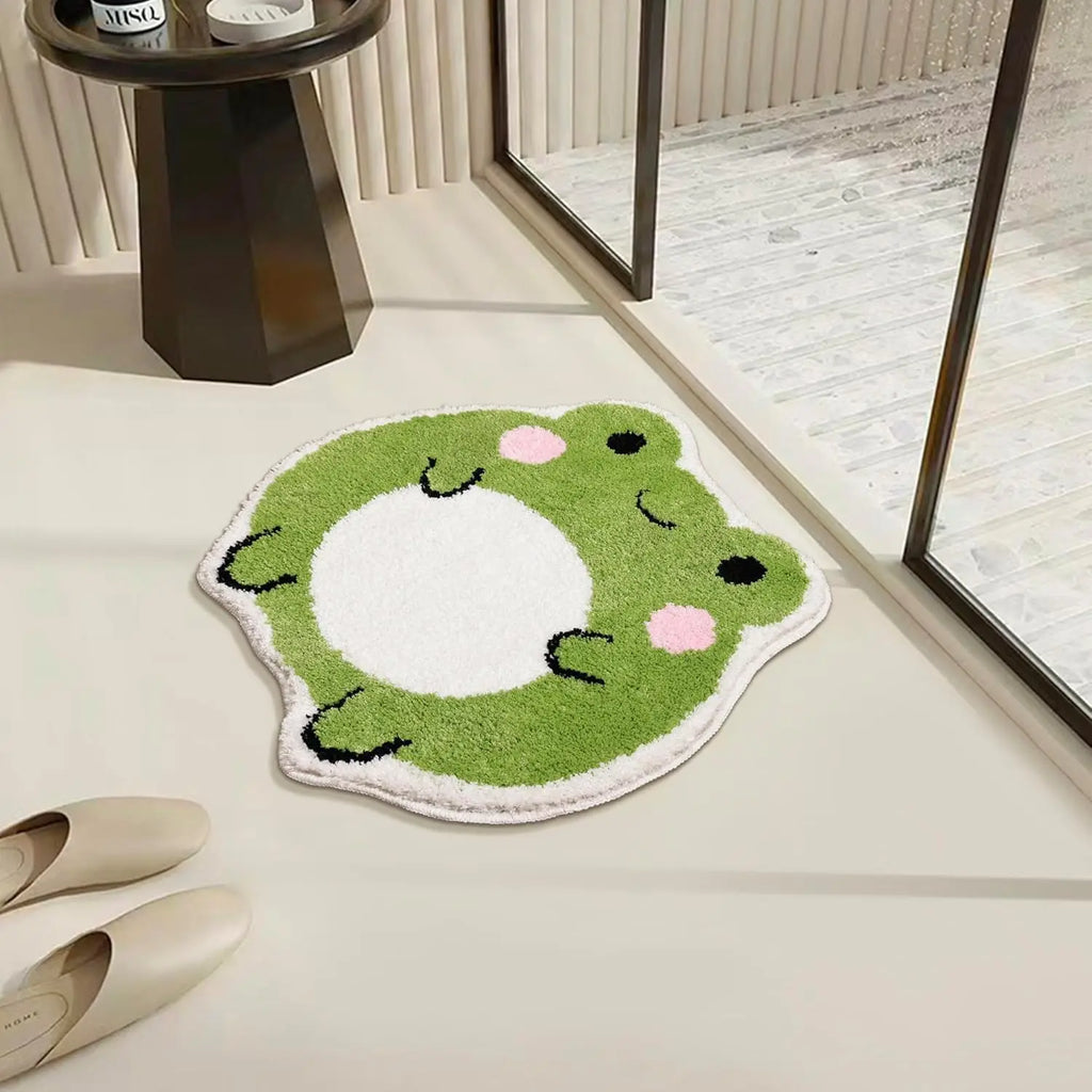 Frog-shaped bath mat placed by a sunlit window, showing soft green and white plush surface
