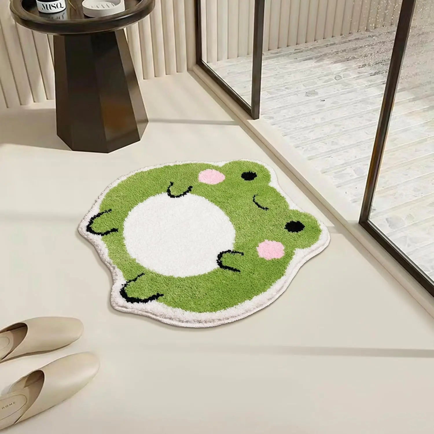 Frog-shaped bath mat placed by a sunlit window, showing soft green and white plush surface