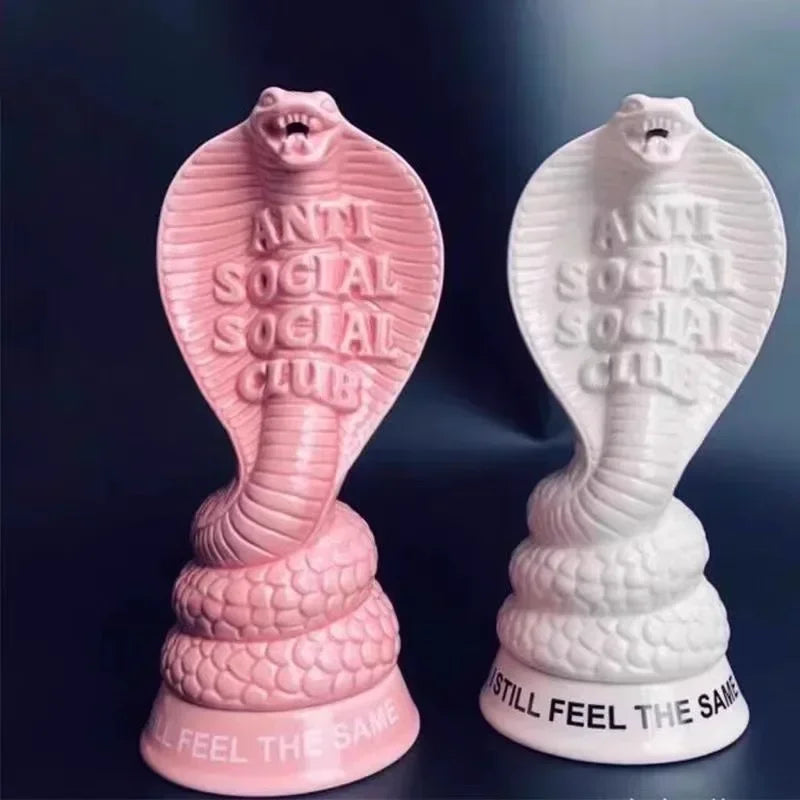 Front view of pink and white cobra-shaped incense holders against dark background