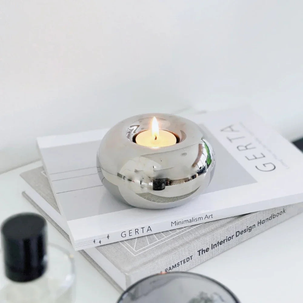 cylinder silver ceramic tealight holder on stacked books in a minimalist living room