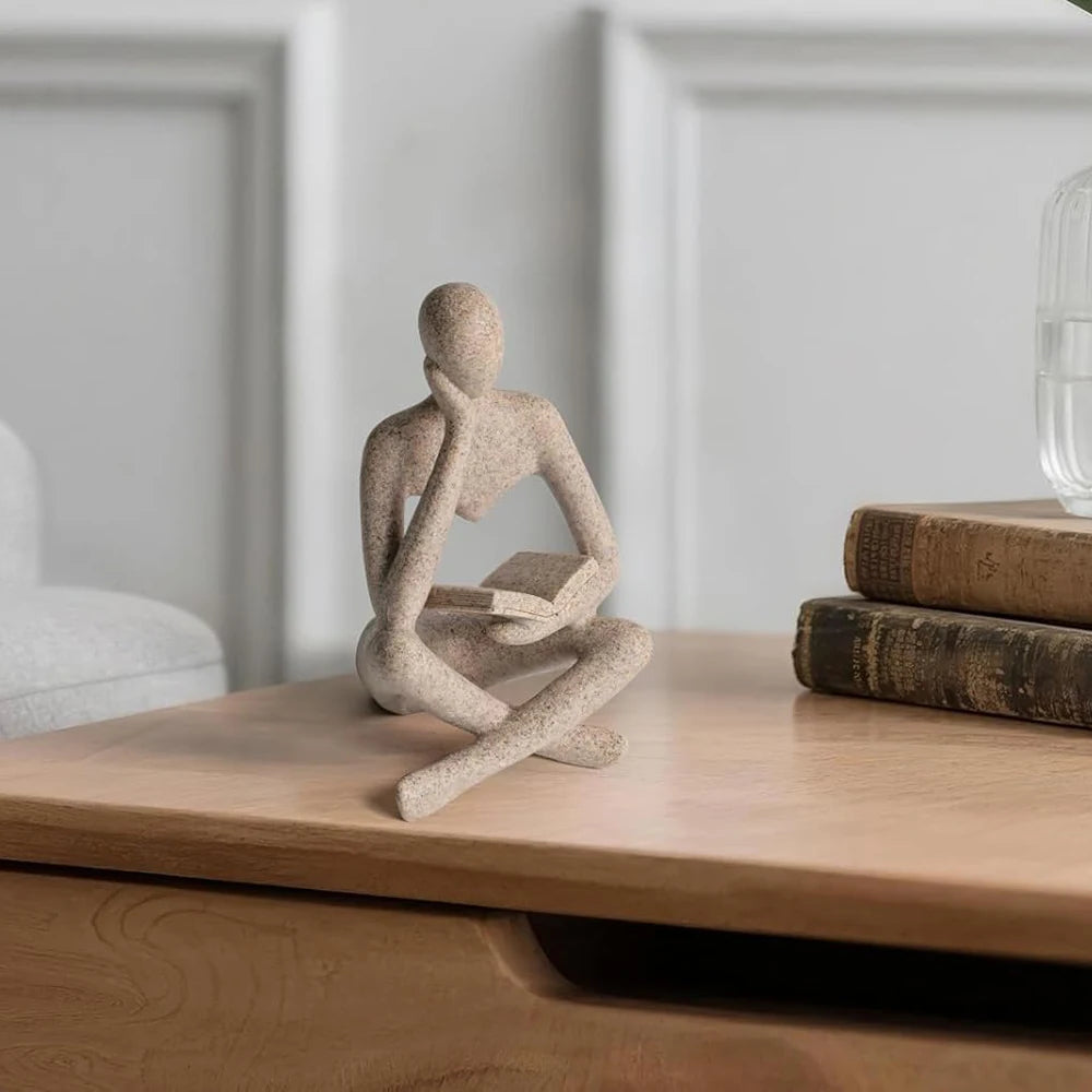 Sculpture displayed on a light wood desk next to stacked hardcover vintage books