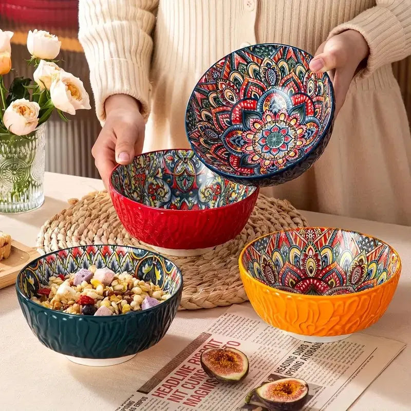 Person holding vibrant Bohemian porcelain bowls with floral pattern, set of four in multicolor on a dining table