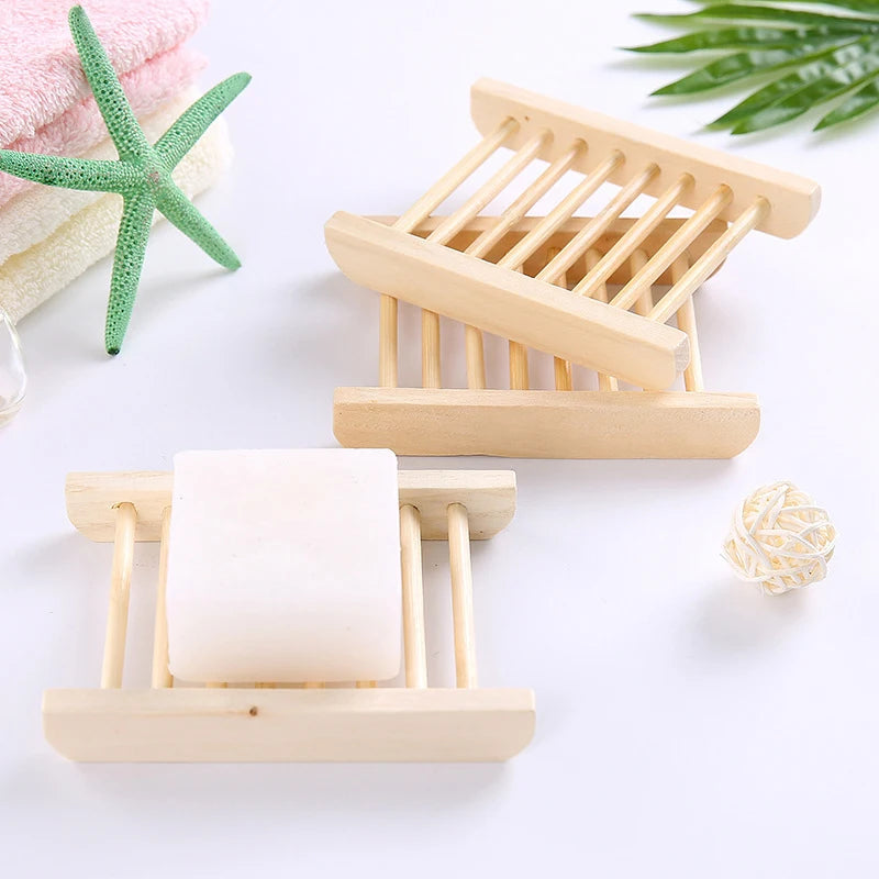 Three wooden soap dishes with bar soap and bathroom accessories