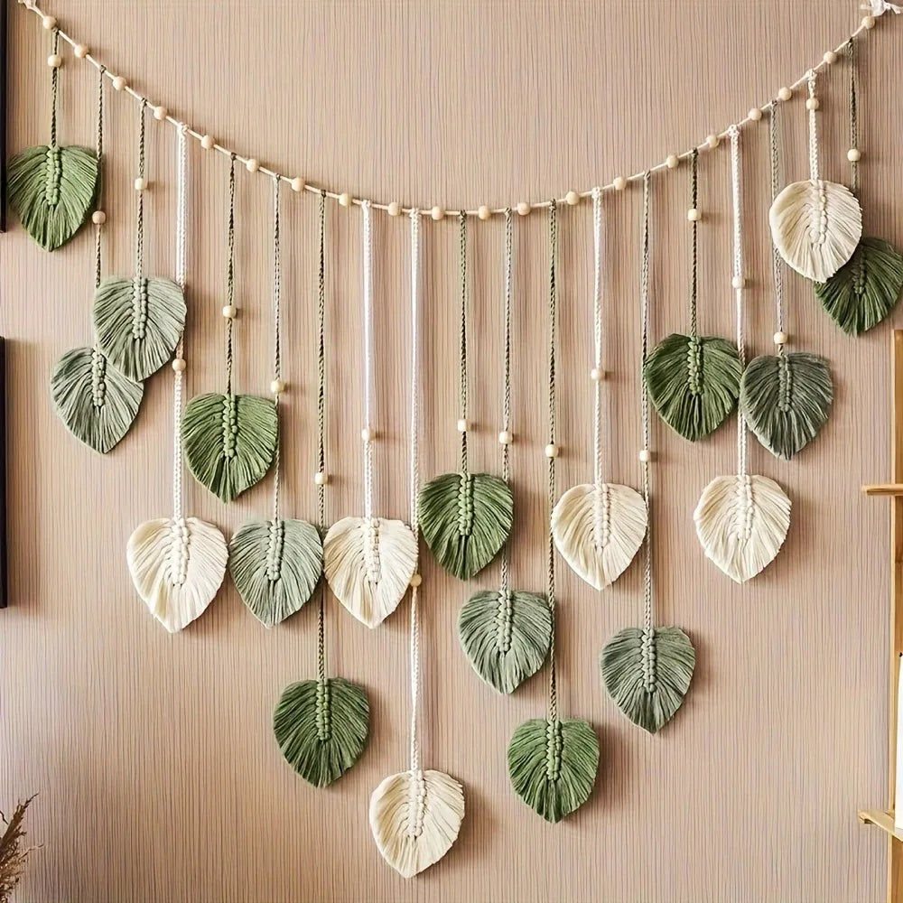 Leaf macrame wall hanging garland with green and cream leaves on a tan wall