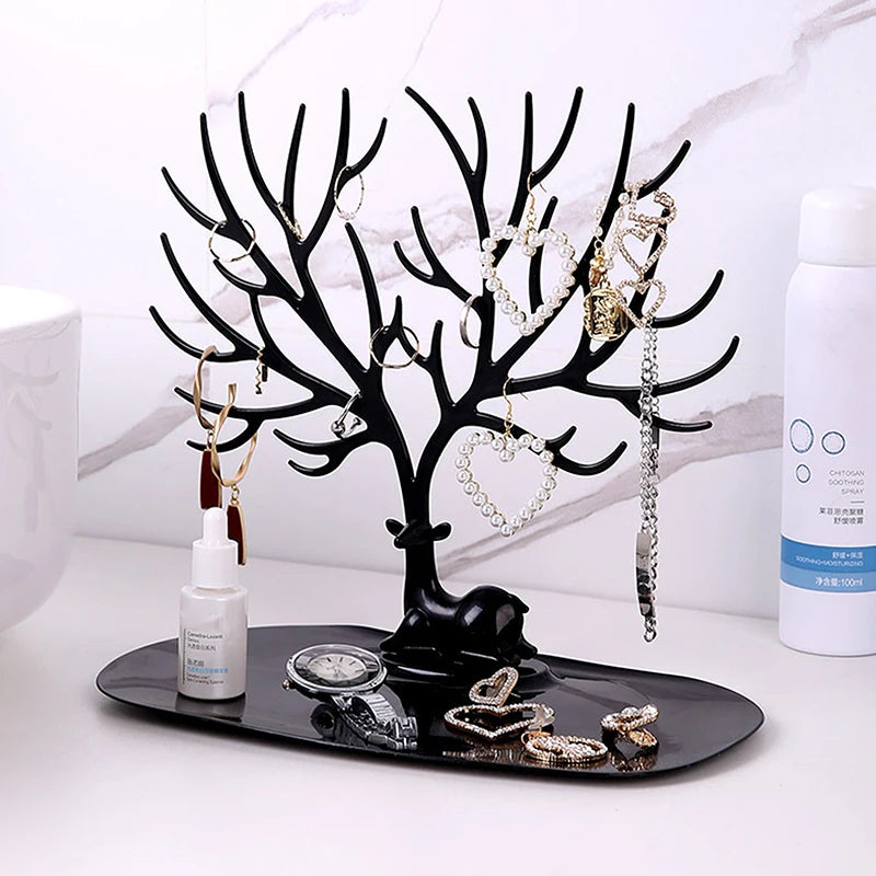 Black reindeer jewelry tree stand with tray on a bathroom vanity, holding assorted jewelry and accessories