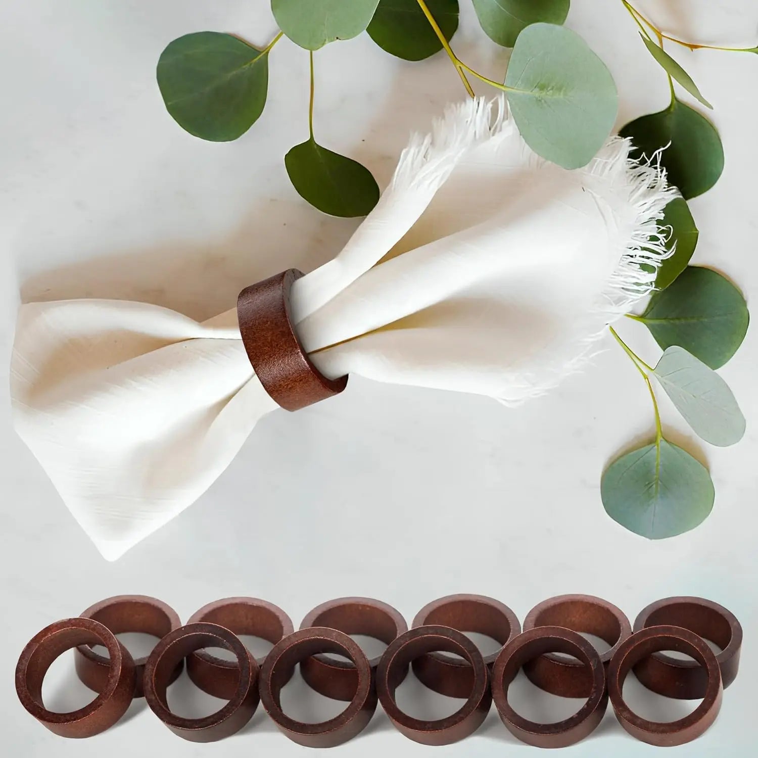 Natural wood napkin ring holding white cloth napkin on a dining table with greenery