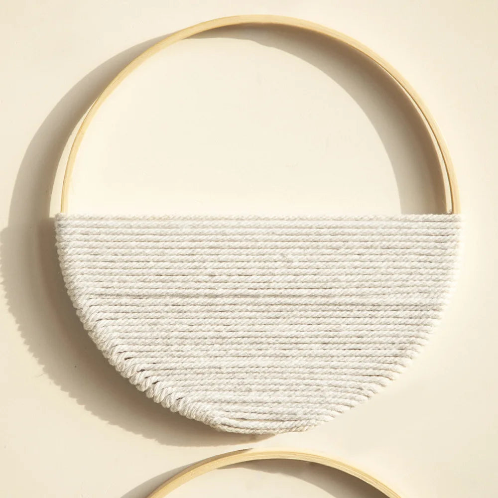 Close-up of the white round macrame wall hanging showing woven cotton texture and smooth wooden ring
