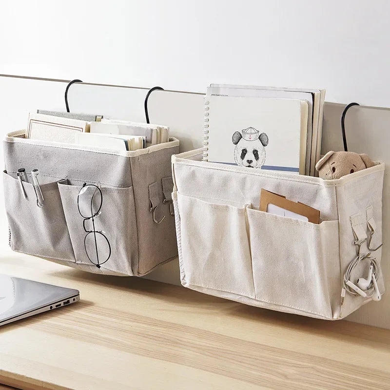 Two fabric hanging organizers, one gray and one beige, hanging from a desk edge and holding books, notebooks, and small essentials