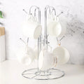 Tree-shaped metal mug holder on a kitchen counter with 6 white mugs hanging