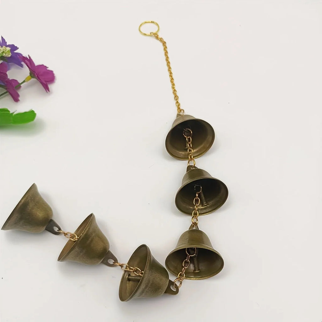 closeup of metal bell wind chime with decorative chain on white background