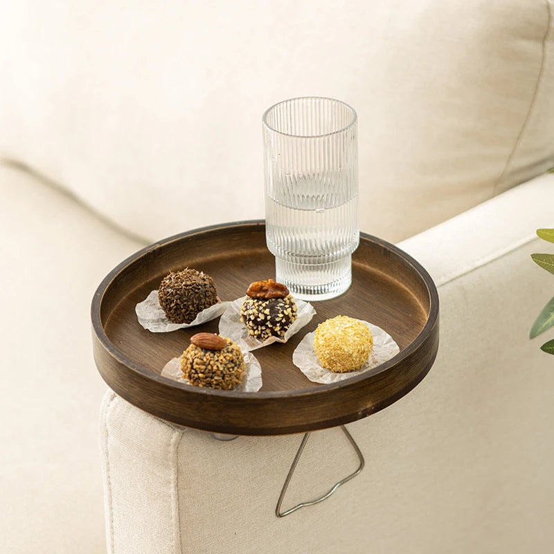 Round walnut bamboo sofa armrest tray holding a glass of water and snacks on cream sofa