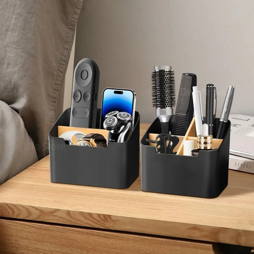 Two black organizers on a nightstand with remotes, phone, pen, and grooming items