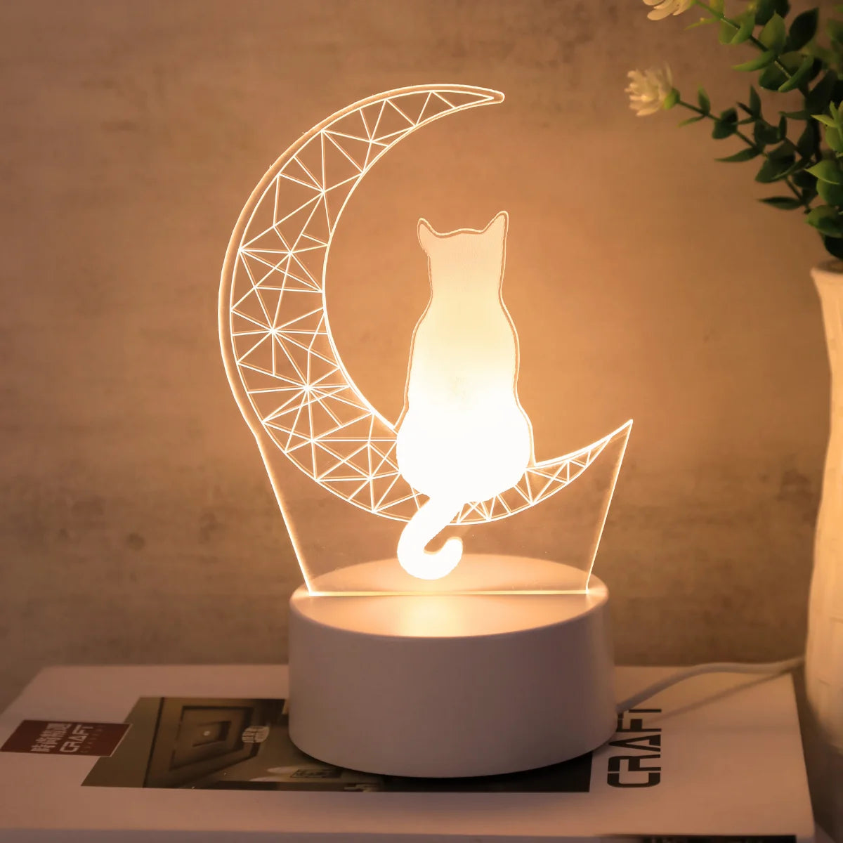Moon cat decorative desk lamp with warm yellow light near a potted plant
