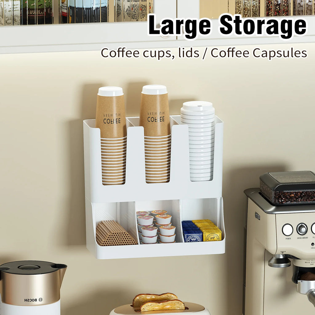 White wall-mounted coffee station organizer with labeled compartments for cups, lids, coffee capsules, and stirrers.