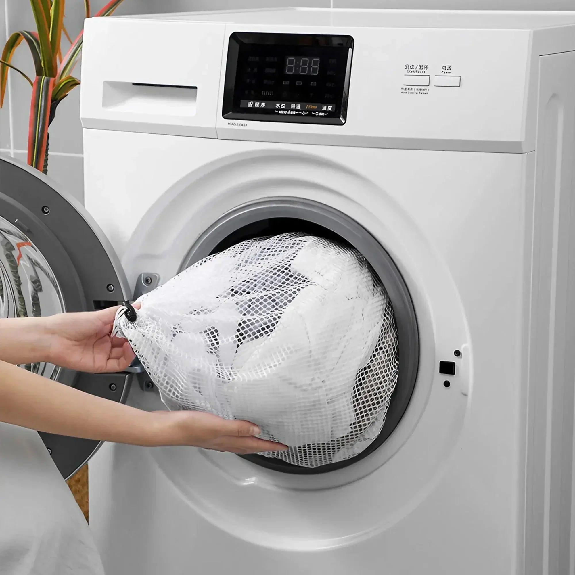 Hands placing a coarse mesh laundry bag filled with clothes into a front-loading washer