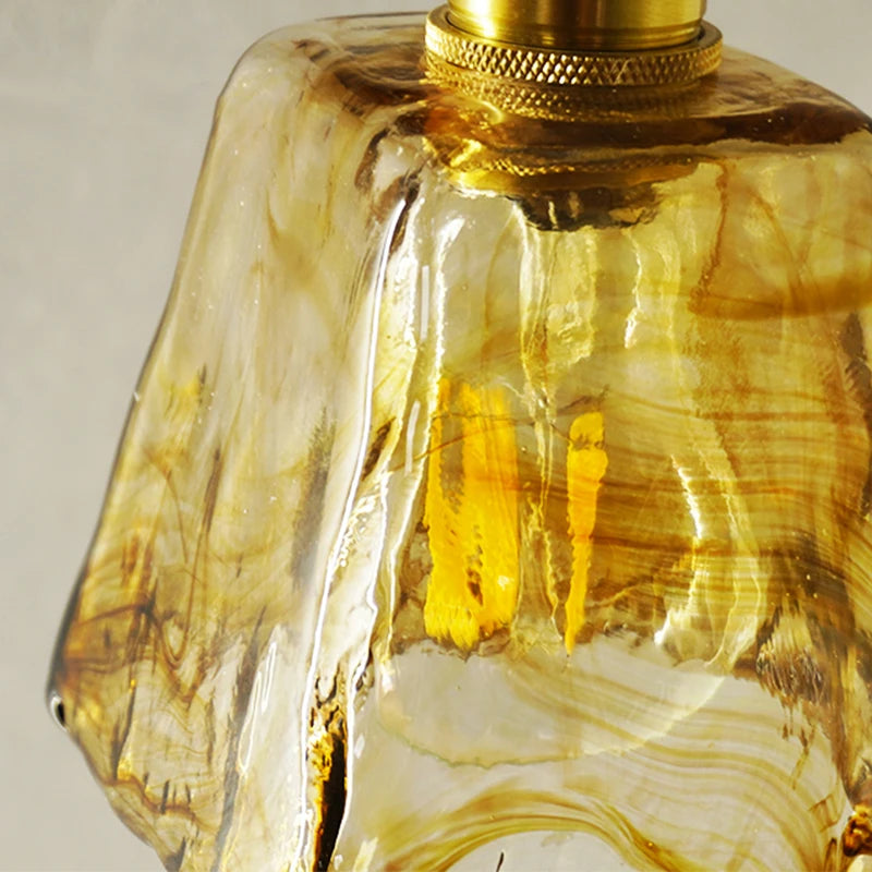 Close-up of amber stained glass shade showing artistic swirled pattern and brass detail