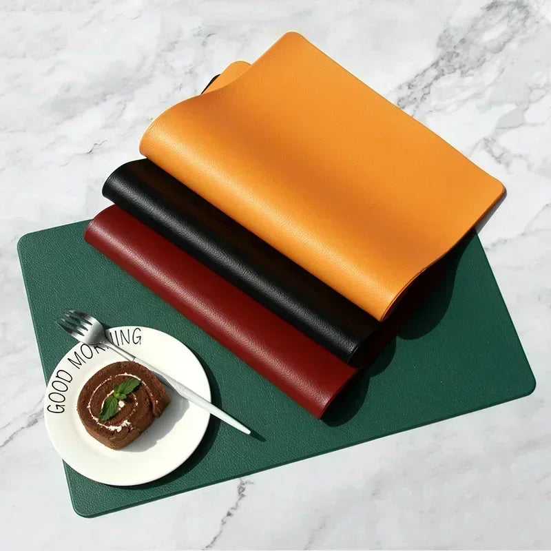 Detail of orange, black, and red PVC rectangular placemats stacked on a green placemat with breakfast plate and fork