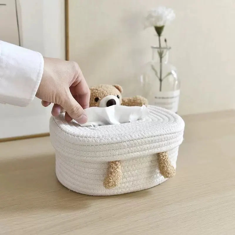 Hand pulling tissue from plush bear cover on light wood tabletop