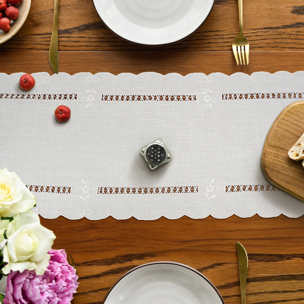 Natural white linen table runner on a set table with floral accents and gold cutlery