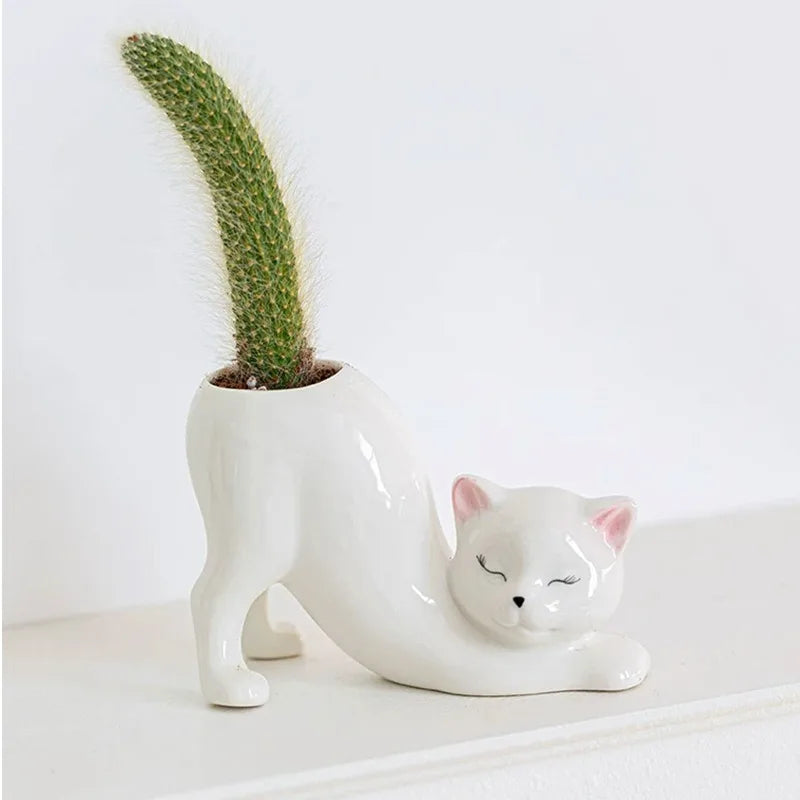 Stretching cat-shaped PVC planter with a cactus on a white shelf