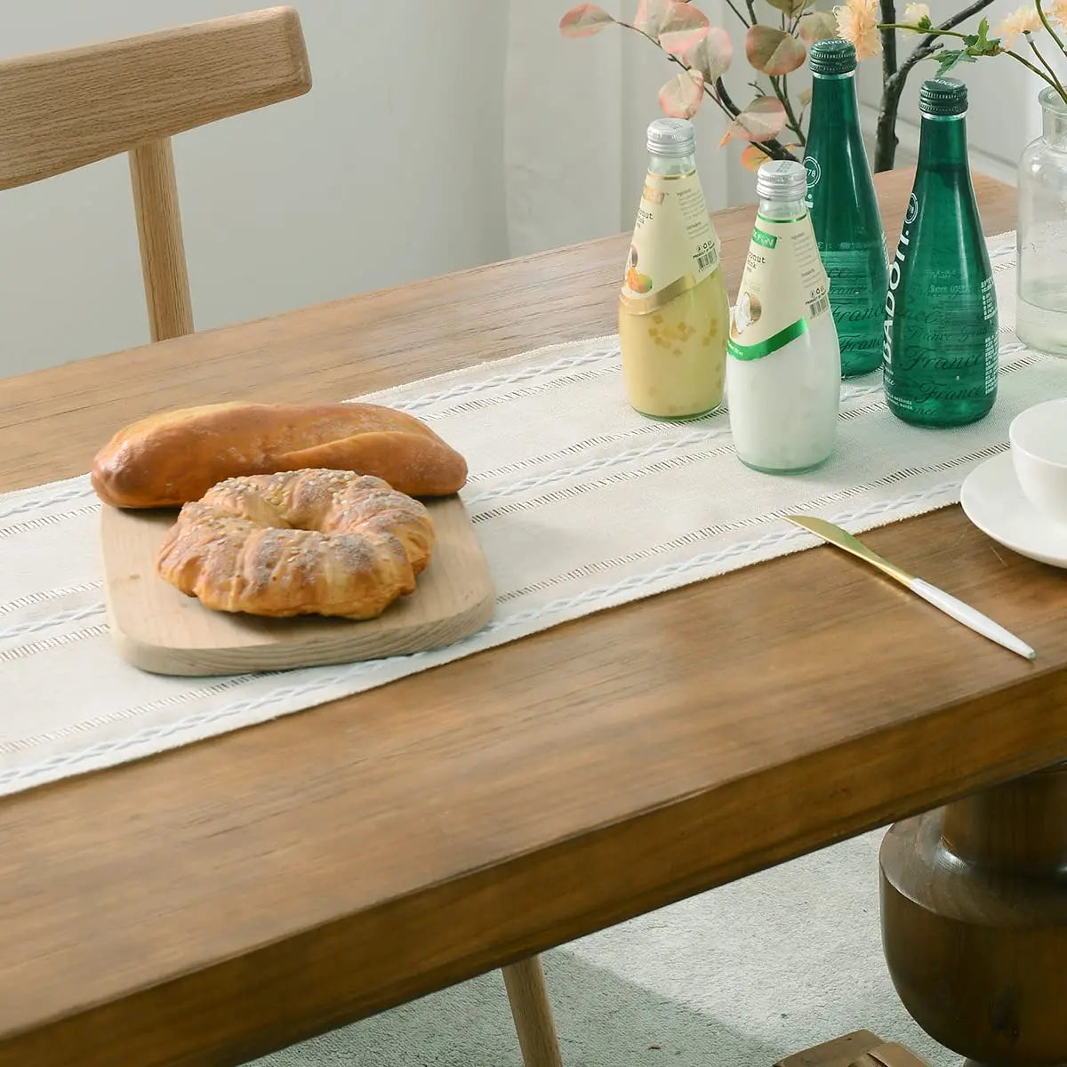 long ivory tasseled table runner styled with drinks and baked goods on a wooden table