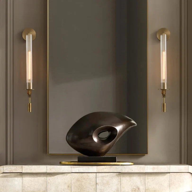 pair of gold glass wall sconces flanking a mirror in a living space