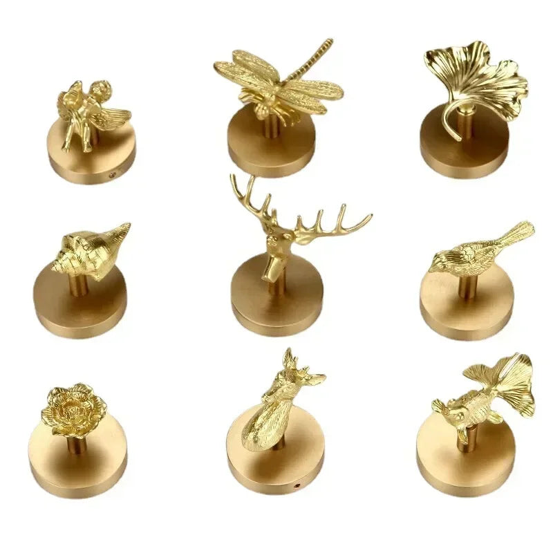 Nine assorted brass animal and botanical wall hooks displayed on white background