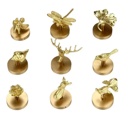 Nine solid brass animal and botanical wall hooks displayed on white background