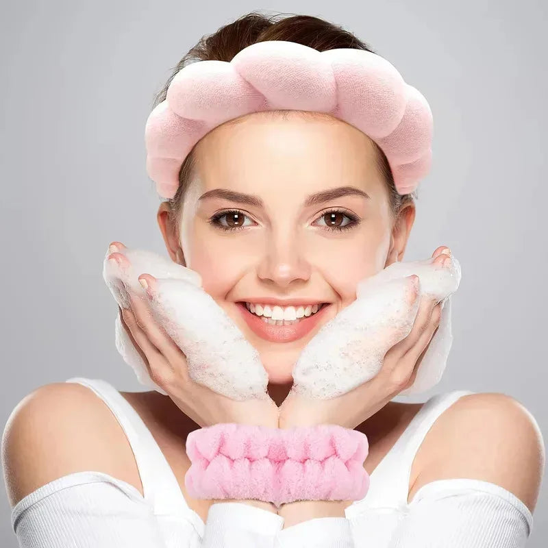 Woman wearing soft pink spa headband and matching wrist straps while washing face