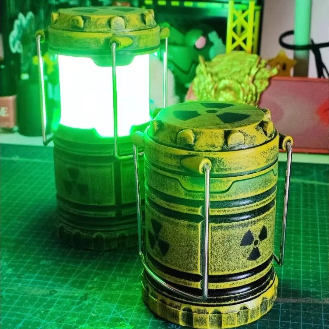 Two mini nuclear reactor lantern night lights, one lit with green glow, on a craft table