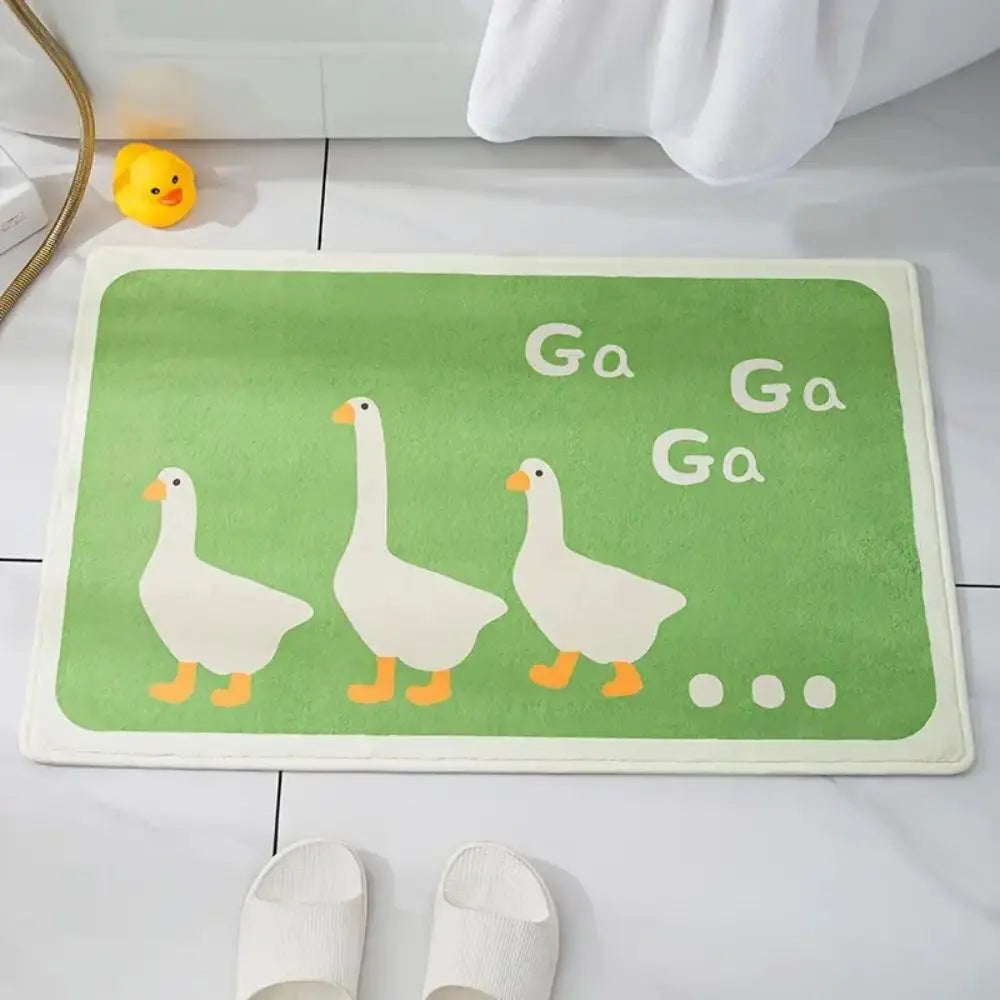 Green duck bath mat with three white ducks and 'Ga Ga' text, placed by a shower