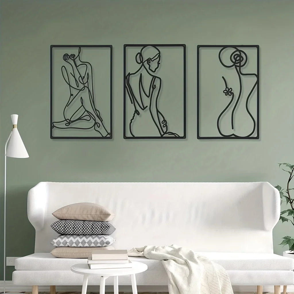 Abstract metal wall art set of three in a minimalist living room above a white sofa and stacked pillows.