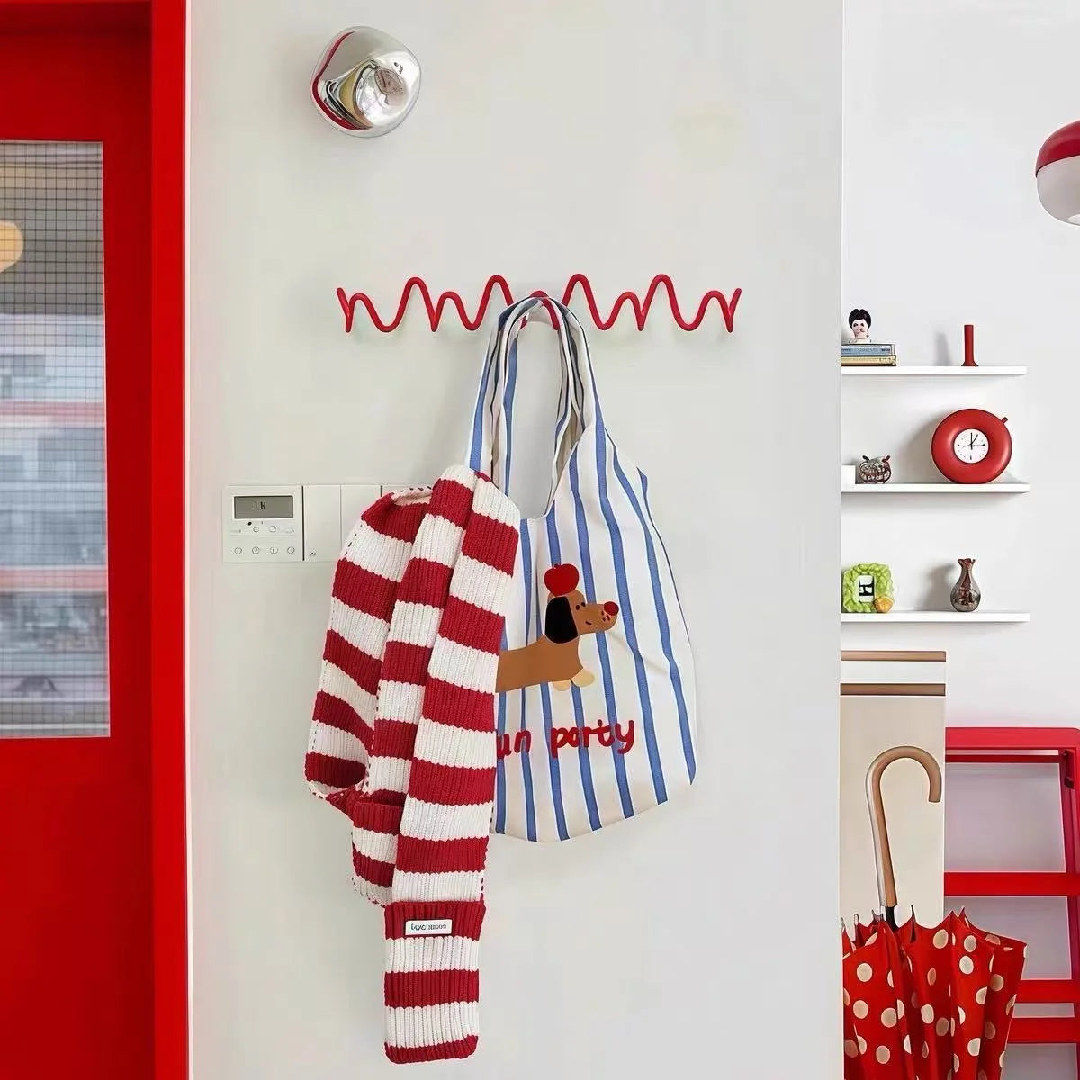 red wave wall hook rack in an entryway holding a striped scarf and a blue tote bag