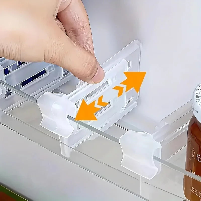 Hand adjusting a clear plastic fridge divider on a refrigerator shelf with orange arrows indicating expandable motion