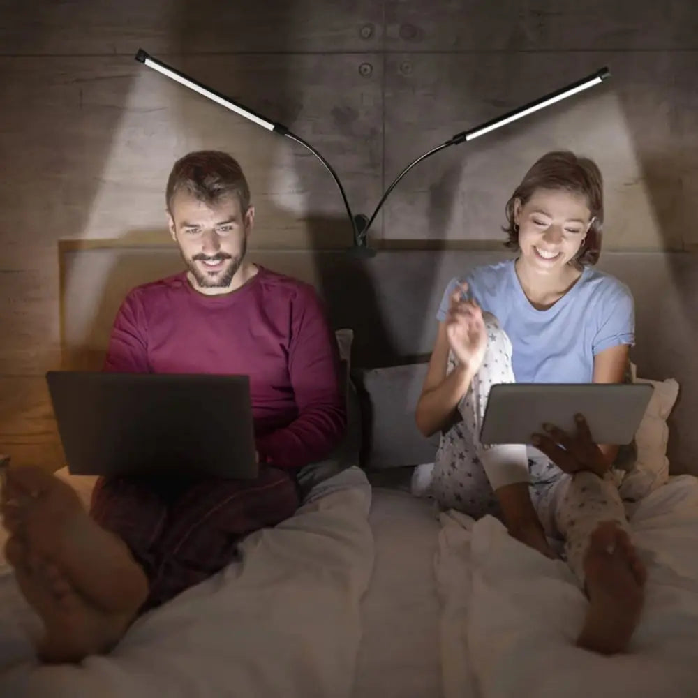 Two people reading in bed using dual-head flexible LED clamp lights attached to the headboard