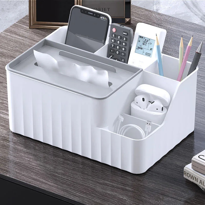 White 6-section desk organizer with tissue box, phone, remotes, pens, and earbuds on a wood table.