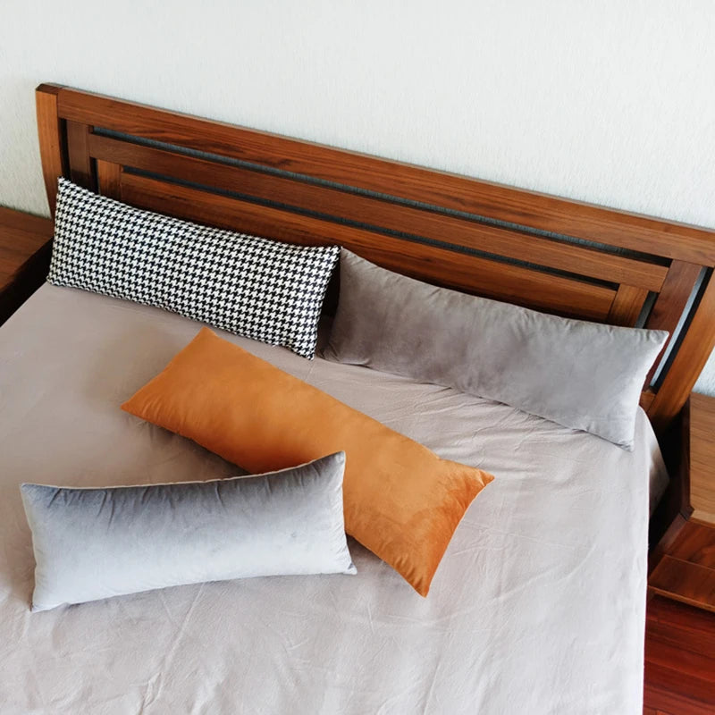 Bed with rectangular velvet and houndstooth pillow covers arranged at the head and center