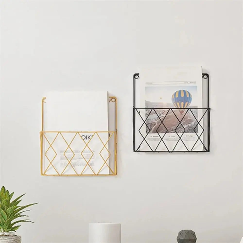 Black and gold metal wall magazine organizers mounted on a wall, each holding reading materials.
