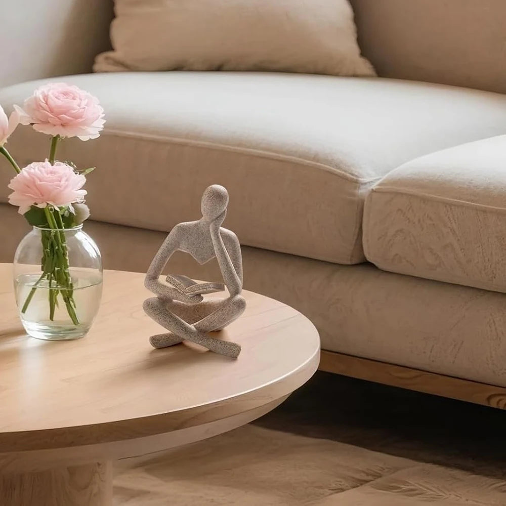 Reader resin sculpture styled on a round coffee table beside flowers in a living room