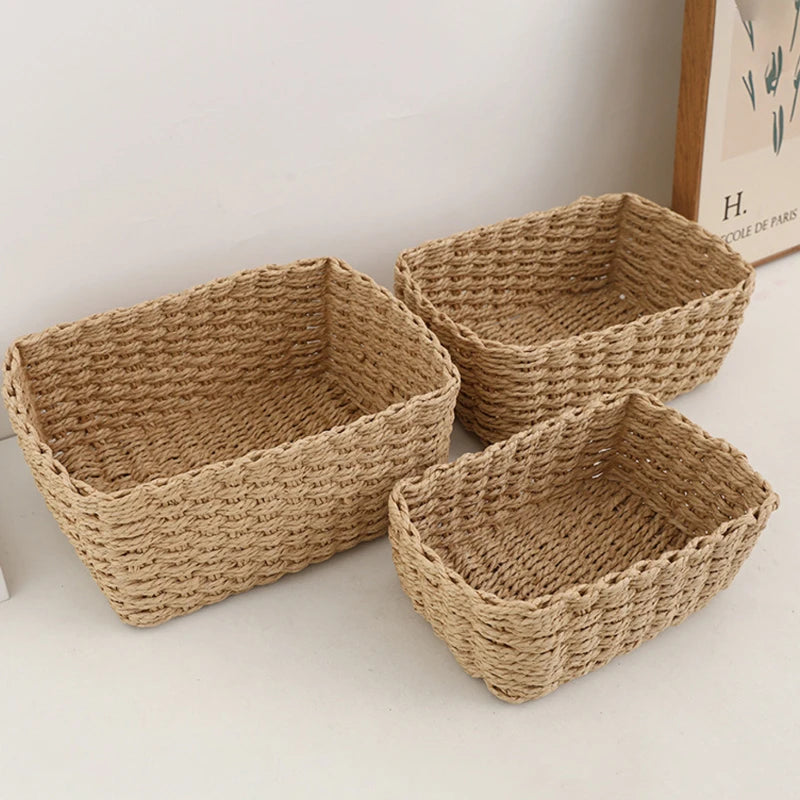 Three beige handwoven storage baskets in different sizes on a white surface