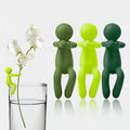 Set of whimsical green plant stem holders, one clipped to a glass holding a white flower stem, others displayed upright