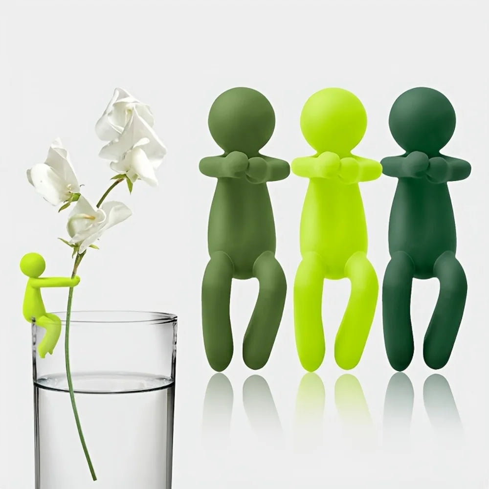Set of whimsical green plant stem holders, one clipped to a glass holding a white flower stem, others displayed upright