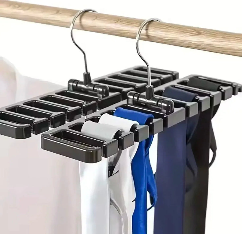 Three black rotating closet organizers holding ties and belts on a wooden rod