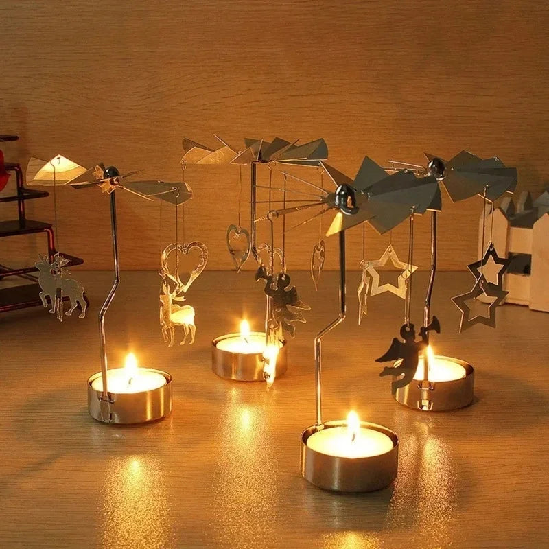 Four rotating tealight candle holders with different hanging charms, each with a candle lit, on a wooden surface