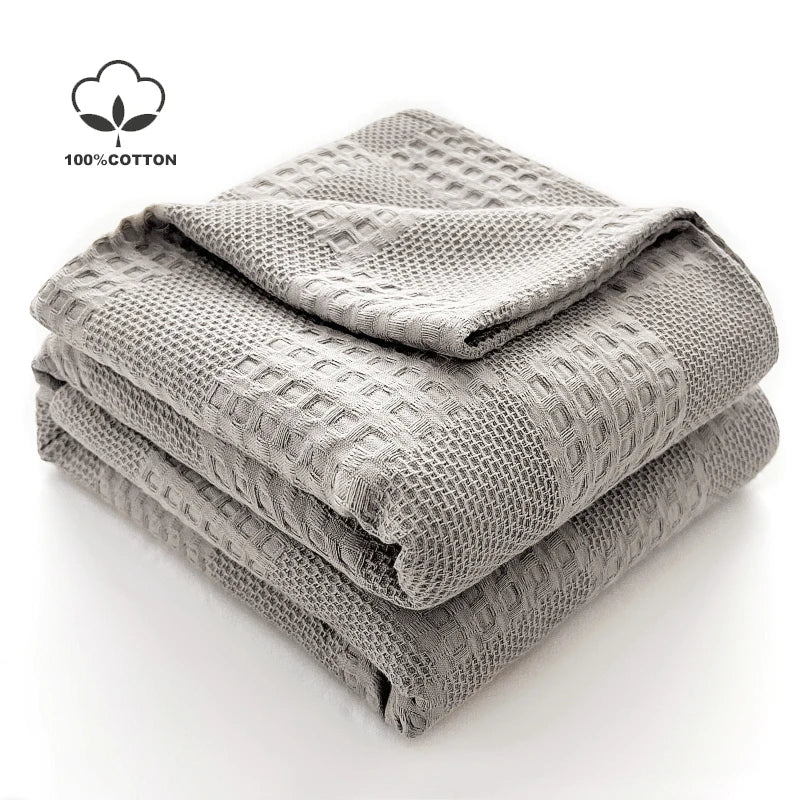 Folded light grey cotton waffle throw blanket showing textured surface