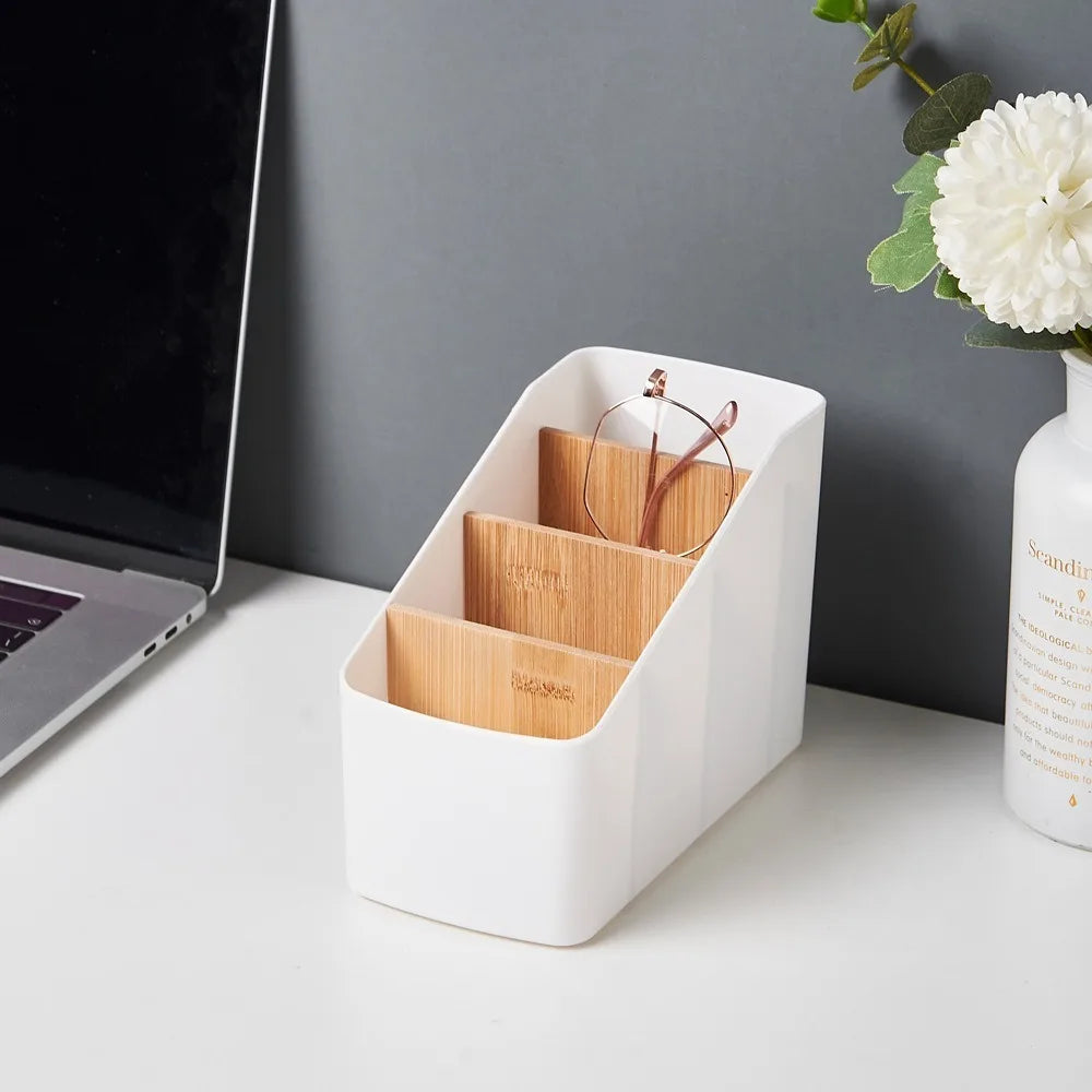 White organizer on desk with glasses in one compartment, beside a laptop and flower vase