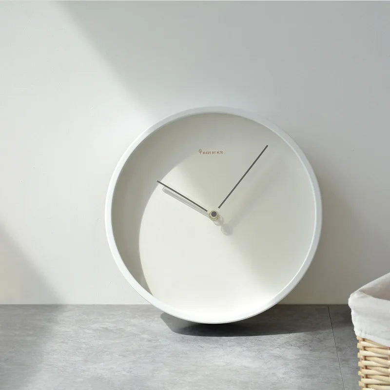 Modern needle wall clock resting against a wall in a cozy room