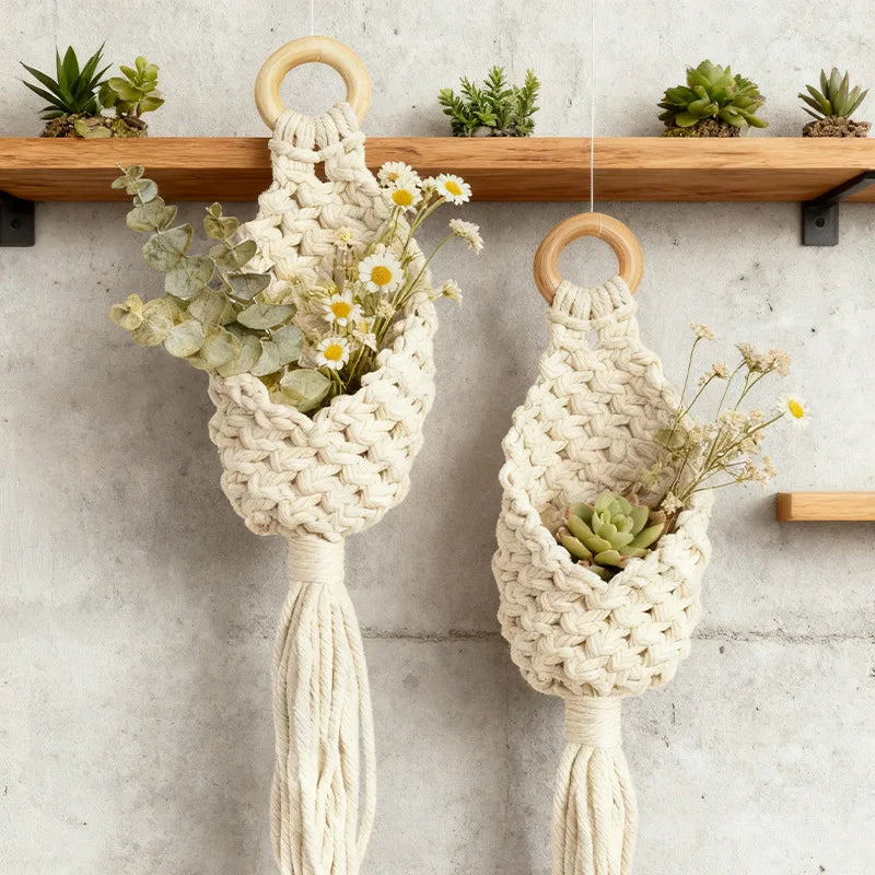 Two cream cotton rope wall baskets with wooden hanging rings, styled with plants and flowers