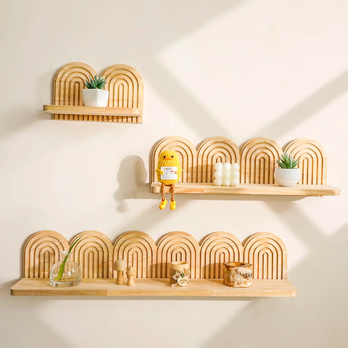 Wall-mounted arched wooden shelves in three sizes displayed with small decorative objects and houseplants